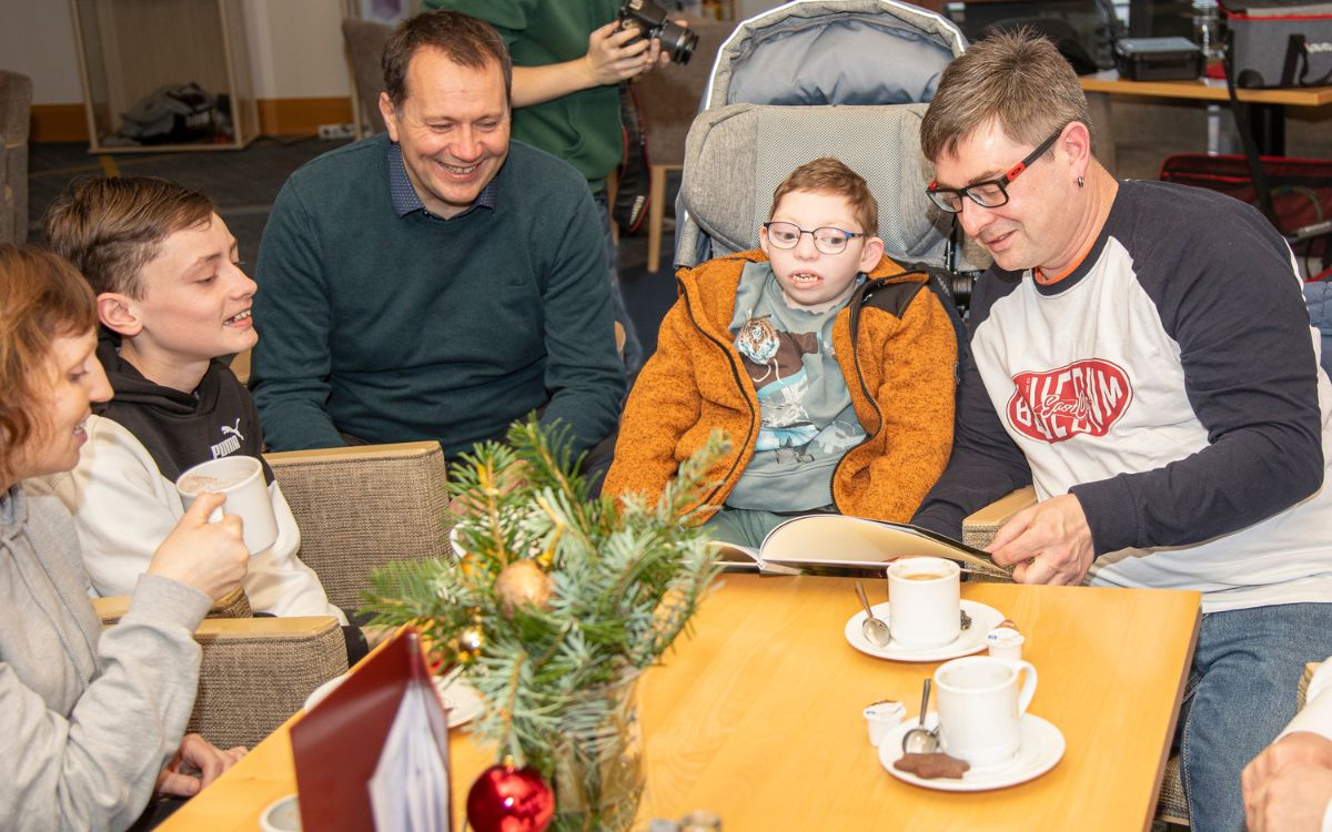 Schmökern im Fotobuch zur Aktion im vergangenen Sommer: v.l. Michaela Storch, Leos Bruder Tim, Hoteldirektor des Kurzentrums Weißenstadt am See, Raik Eilert, Leo Storch und sein Vater Robert. Foto: Gesell GmbH